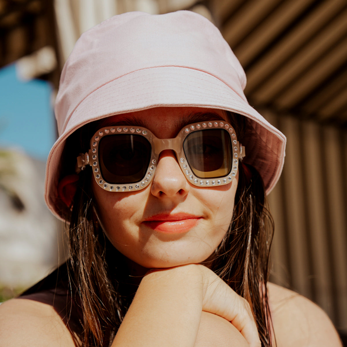teen girl sitting poolside wearing bring vibrancy swim goggles in opal showing wide square framed swim goggles with rhinestones and tinted lens